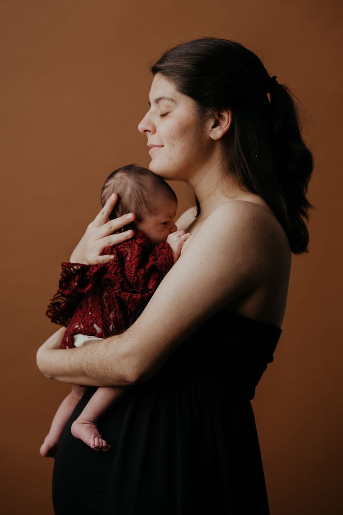 Mãe acolhendo seu bebê no colo, em uma fotografia ilustrativa